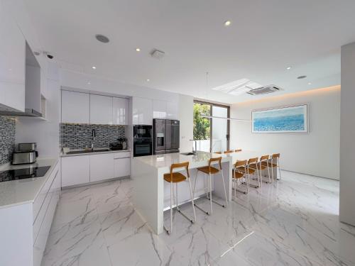a kitchen with white cabinets and a table and chairs at 3BR Private Pool Villa near Laguna & Beach - Residence Villa by Warm Plus in Ban Pak Lak