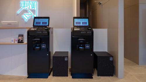 duas máquinas de caixa eletrônico com monitores em cima delas em Toyoko Inn Kochi em Kochi