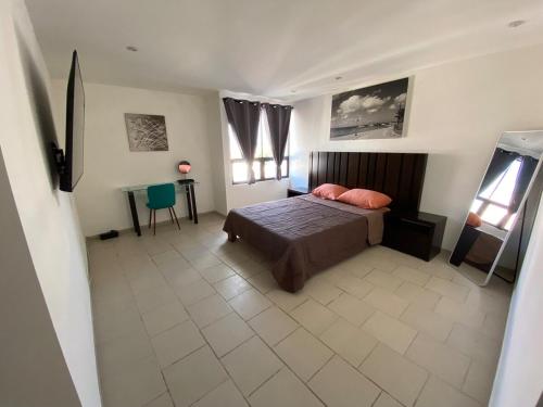 a bedroom with a bed and a table and windows at Moderno depa con todas las comodidades en Juriquilla, Queretaro in Juriquilla