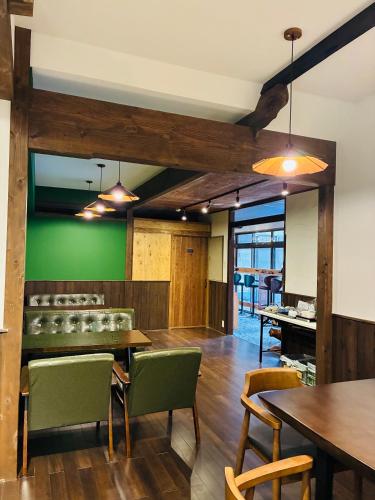 a restaurant with green walls and wooden tables and chairs at Guest house Mitaki in Hiroshima