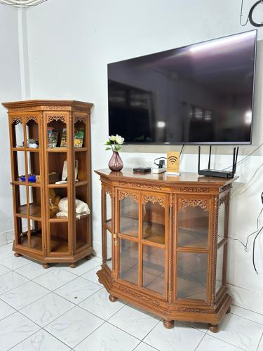 zwei hölzerne Unterhaltungsmöbel mit einem Flachbildfernseher an der Wand in der Unterkunft Wooden Friend House in Krabi