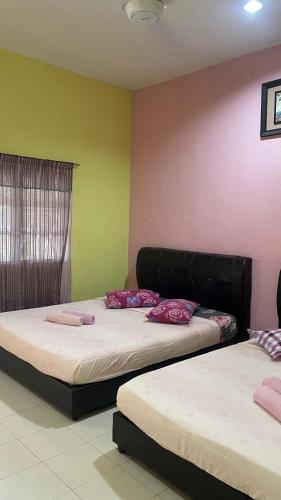 two beds in a room with pink and green walls at Teratak Atok Ajib in Pantai Cenang