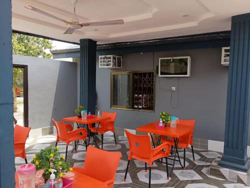 een terras met oranje tafels en stoelen en een muur bij Groove Vacation Homes in Kasoa