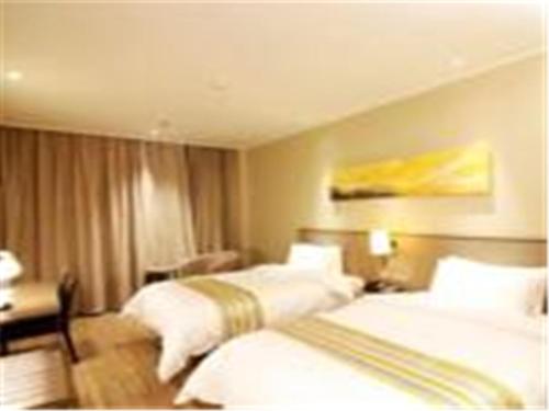 a hotel room with two beds and a desk at Home Inn Ji'nan Dikou Road Railway Station North Square in Jinan