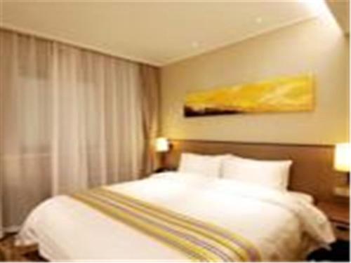 a hotel room with a bed and a painting on the wall at Home Inn Ji'nan Dikou Road Railway Station North Square in Jinan