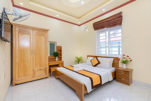 a bedroom with a bed and a desk and a window at Hoàng My Villa - 100m tới bãi tắm Long Cung in Vung Tau