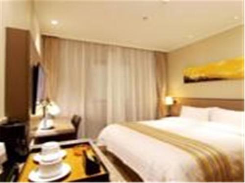 a hotel room with a bed and a coffee table at Home Inn Ji'nan Dikou Road Railway Station North Square in Jinan
