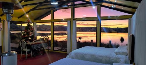 a bedroom with a large window with a view of a lake at Los uros Domo Atardecer in Puno