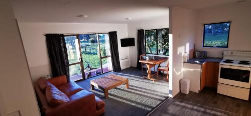 een woonkamer met een bank en een tafel bij The Barnyard Cottage in Otakiri