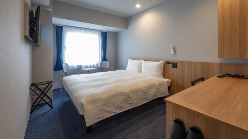 a hotel room with a bed and a window at Toyoko Inn Kochi in Kochi