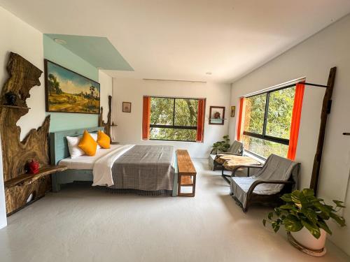 a bedroom with a bed and a table and windows at Gallery House - Artistic Villa with Plunge Pool in Phumĭ Réach Born (1)