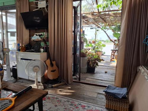 a living room with a fan and a guitar in it at Baan GoLite Ko Kret - บ้านโกไล้เกาะเกร็ด in Nonthaburi