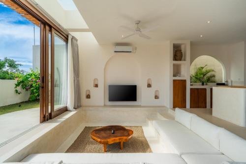 a living room with a white couch and a table at Villa Cove 5 by BaliSuperHost in Uluwatu