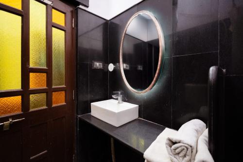 une salle de bain noire avec un lavabo et un miroir dans l'établissement Hotel The Vintage villa Jaisalmer, à Jaisalmer