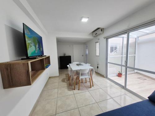 un soggiorno con un tavolo e una TV a parete di Excelente departamento con 2 patios en Zona Aldrey a Mar del Plata
