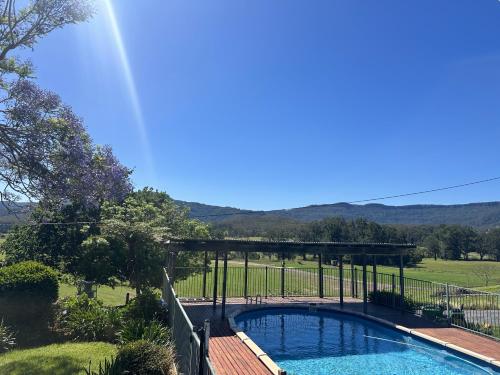 a swimming pool in a yard with a bridge over it at Hillview Studio One in Berry