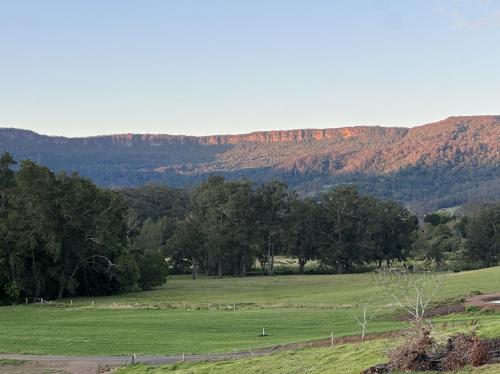 a field with trees and mountains in the background at Hillview Studio One in Berry