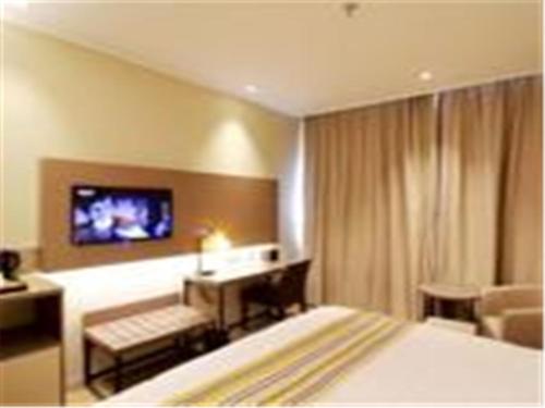 Home Inn Ji'Nan Jiefang Road في جينان: غرفة في الفندق بها سرير وتلفزيون على الحائط