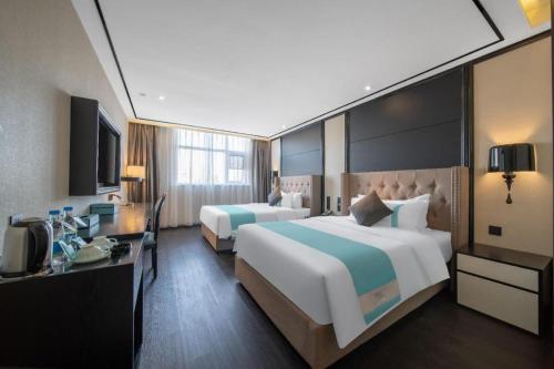 een hotelkamer met twee bedden en een televisie bij Xana Hotelle Jinan Daminghu North Gate in Jinan