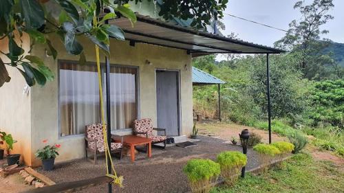 une maison avec un porche avec deux chaises et un banc dans l'établissement Solitary Cottage Dunhinna, à Teldeniya