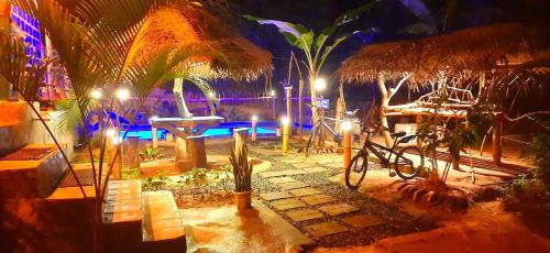 a patio with a table and a bicycle and lights at Sky Blue Cabin in Kandy