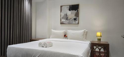 a bedroom with a white bed with two towels on it at Nakula at Waterplace Residence in Surabaya
