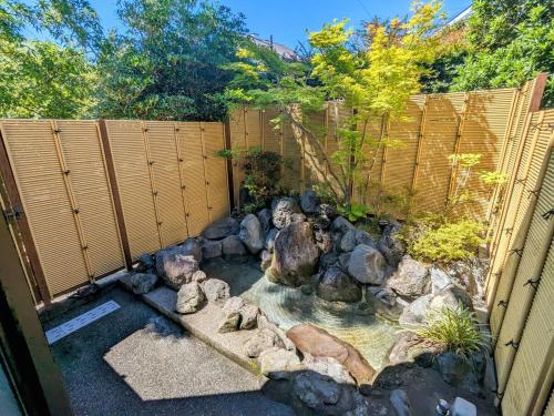 伊东SAKURA Cottage Izukogen的后院设有池塘、岩石和围栏