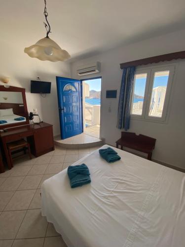 a bedroom with a bed and a blue door at Elpis Rooms in Mylopotas