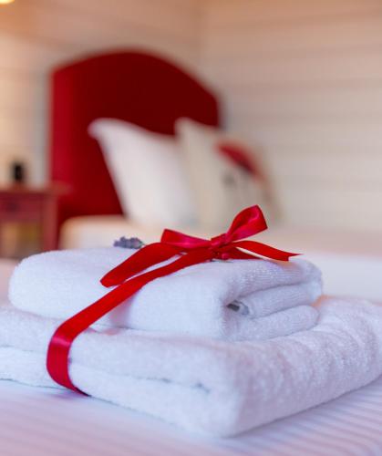 a stack of towels with a red ribbon on a bed at Ktima Noosfera Wellness & Retreat Center in Nees Vrisoules