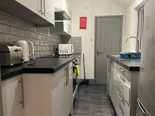 a kitchen with white cabinets and black counter tops at Shelton Guest House in Stoke on Trent