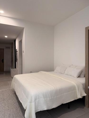 a white bedroom with a large white bed at StayCO - D'Millenia Residences - Studio Unit in Kuching