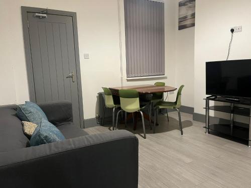 a living room with a couch and a table and a television at Shelton Guest House in Stoke on Trent