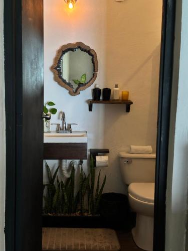 a bathroom with a sink and a toilet and a mirror at Casa China Guesthouse & Hostal in Bacalar