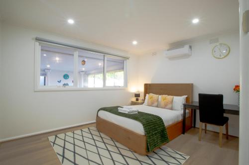 a bedroom with a bed and a desk and a window at Pool, Games & fun - Family Retreat! in Boronia
