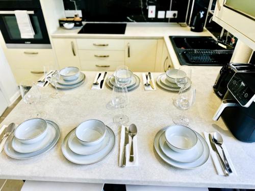 une table avec des assiettes et des verres à vin dessus dans l'établissement Ama comfort Stay, à Hythe