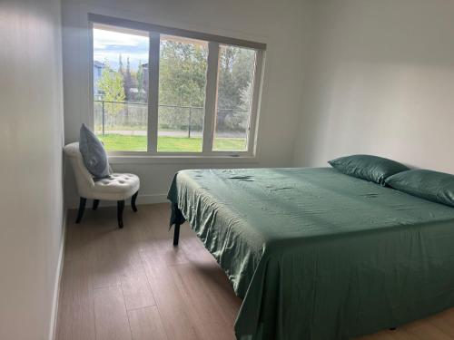 Un dormitorio con una cama, una silla y una ventana en Walkout basement suite with canal view near airport, en Airdrie