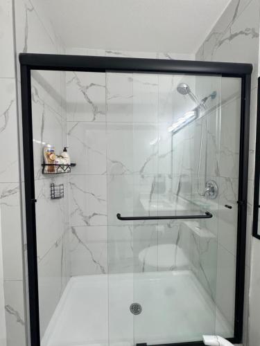 una ducha con puerta de cristal en un baño en Walkout basement suite with canal view near airport, en Airdrie