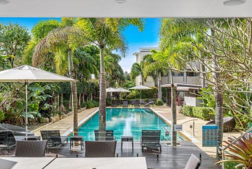 an image of a swimming pool at a resort with palm trees at Bali Luxury Resort - Holiday Management in Kingscliff