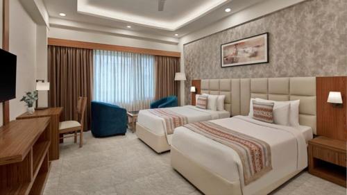 a hotel room with two beds and a desk at The Fern Residency, Bodhgaya in Bodh Gaya