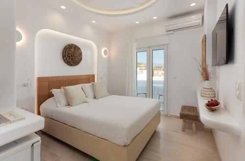 Un dormitorio blanco con una cama y un balcón. en Margo Studios, en Naxos Chora