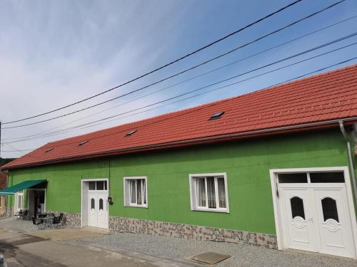 een groen en wit gebouw met een rood dak bij La Nera in Sasca Română