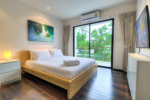 Un dormitorio con una cama y una ventana grande en The Title Comfort Condotel, en Rawai Beach