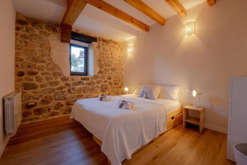 a bedroom with a bed and a stone wall at The Stone House naturaleza y confort in Santibáñez de Villacarriedo