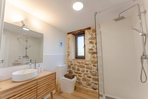 a bathroom with a sink and a toilet and a mirror at The Stone House naturaleza y confort in Santibáñez de Villacarriedo