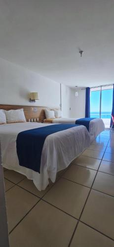 een slaapkamer met een groot bed met blauw-witte lakens bij Hotel Playamar in Mazatlán