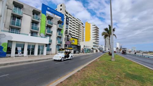 a white car driving down a city street with buildings at Hotel Playamar in Mazatlán