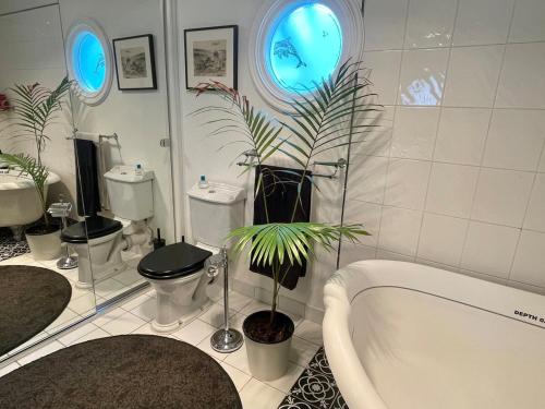 une salle de bain avec une baignoire, deux toilettes et une plante dans l'établissement PET Friendly Miners Cottage 'Baraka BnB', à Kalorama
