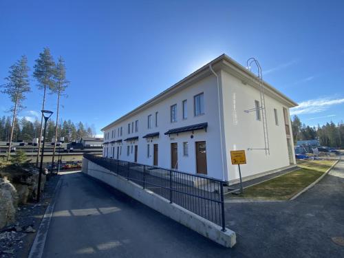 un bâtiment blanc avec une clôture devant dans l'établissement Convenient Apartment for 4 with Sauna, à Seinäjoki