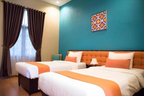 Dos camas en una habitación con una pared azul. en Ole Suite Hotel, en Bogor