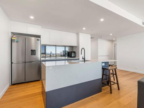 a kitchen with white cabinets and a stainless steel refrigerator at Skyline Showdown - Views, Games & Vibes in Gold Coast